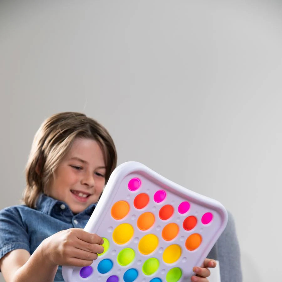 Child holding a colourful pop-it fidget toy against a plain background