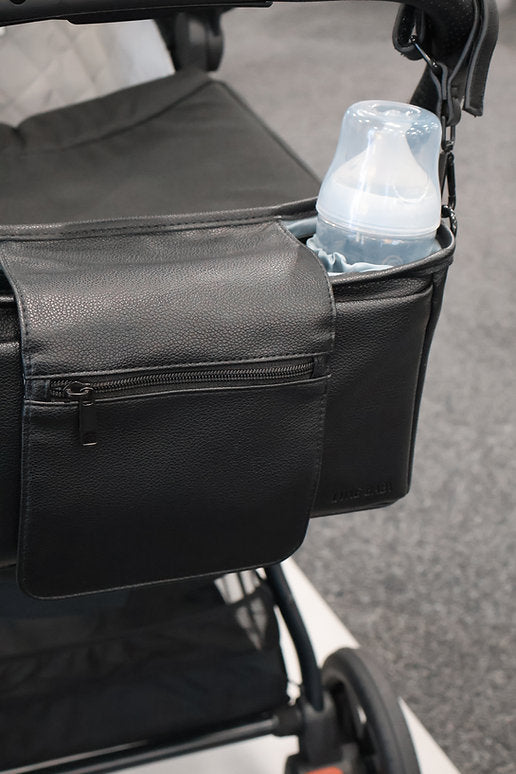 Black stroller organizer with a insulated container on a sidewalk