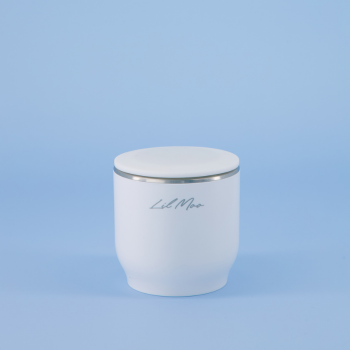 Lil Moo Bottle Warmer with silver lid on a light blue background