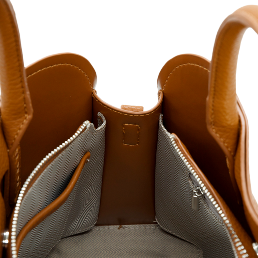 Close-up of a brown vegan leather handbag with a zipper pocket on a white background
