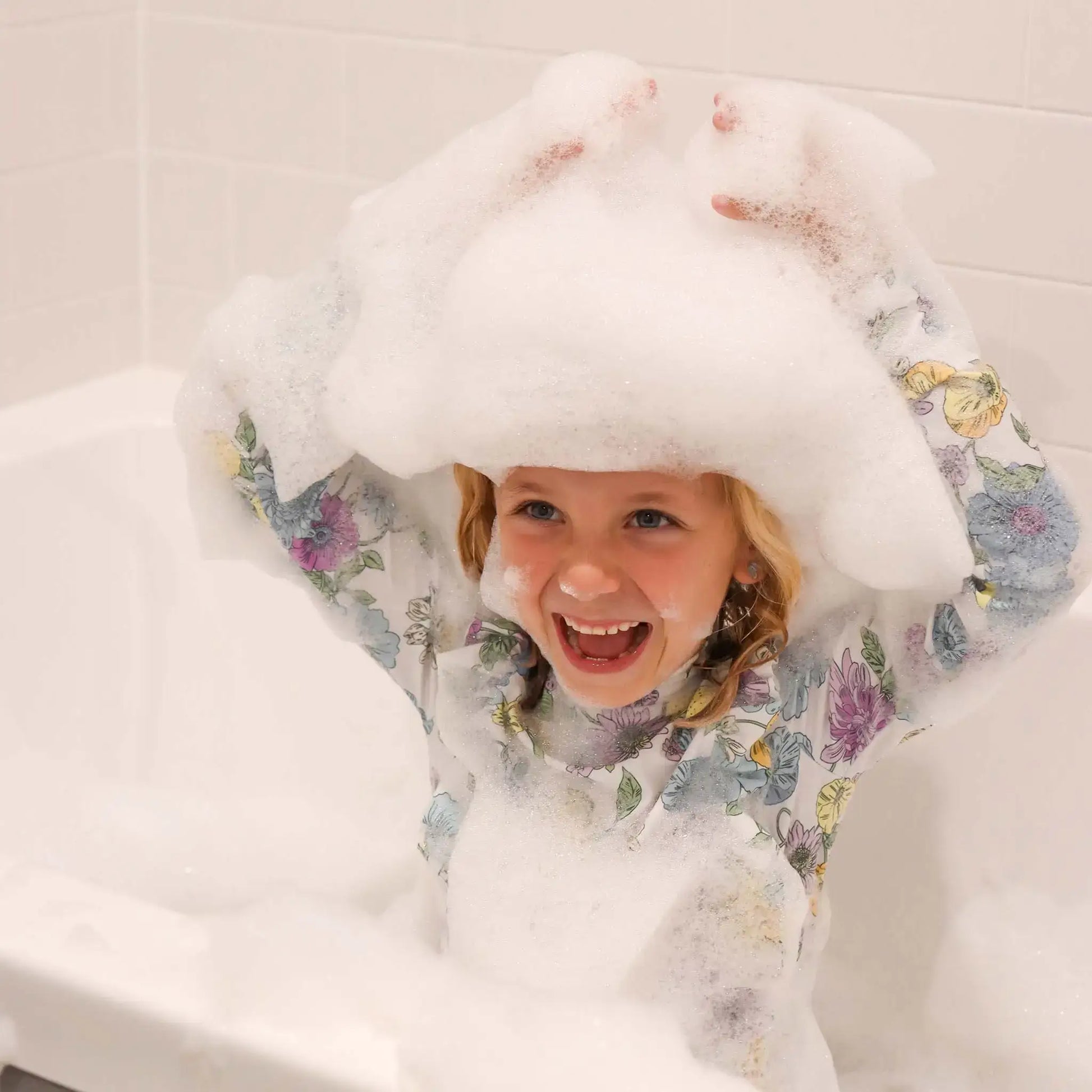 Child using Honeysticks Bubble Bath in a floral swimsuit