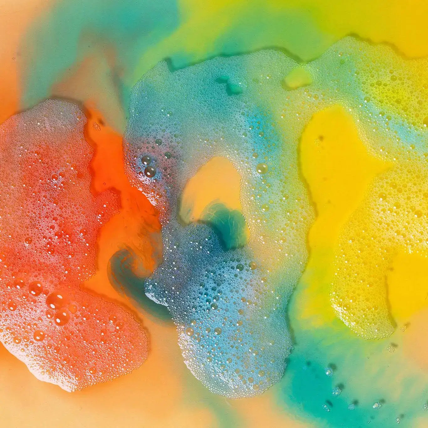 Colourful foam from Honeysticks Bubble Bath with orange, yellow, and blue hues.
