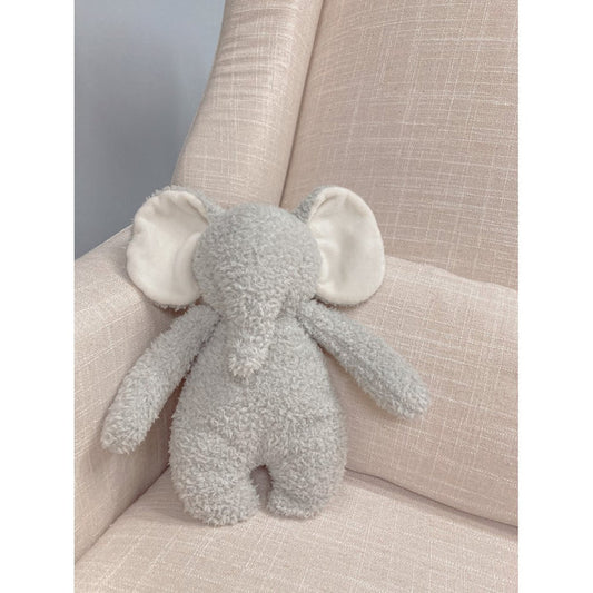 Plush elephant toy on a beige cushion