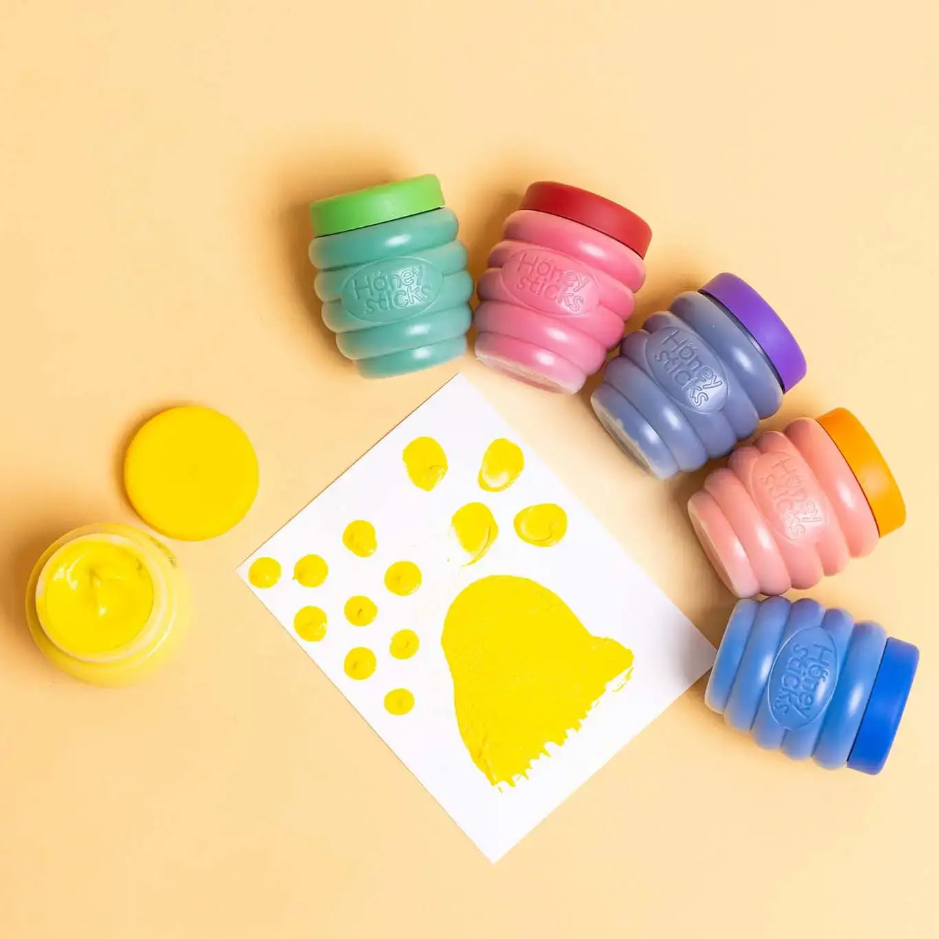 Colourful stampers with a yellow paw print template on a beige background