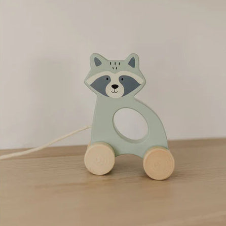 Wooden raccoon toy on a wooden surface with a plain background