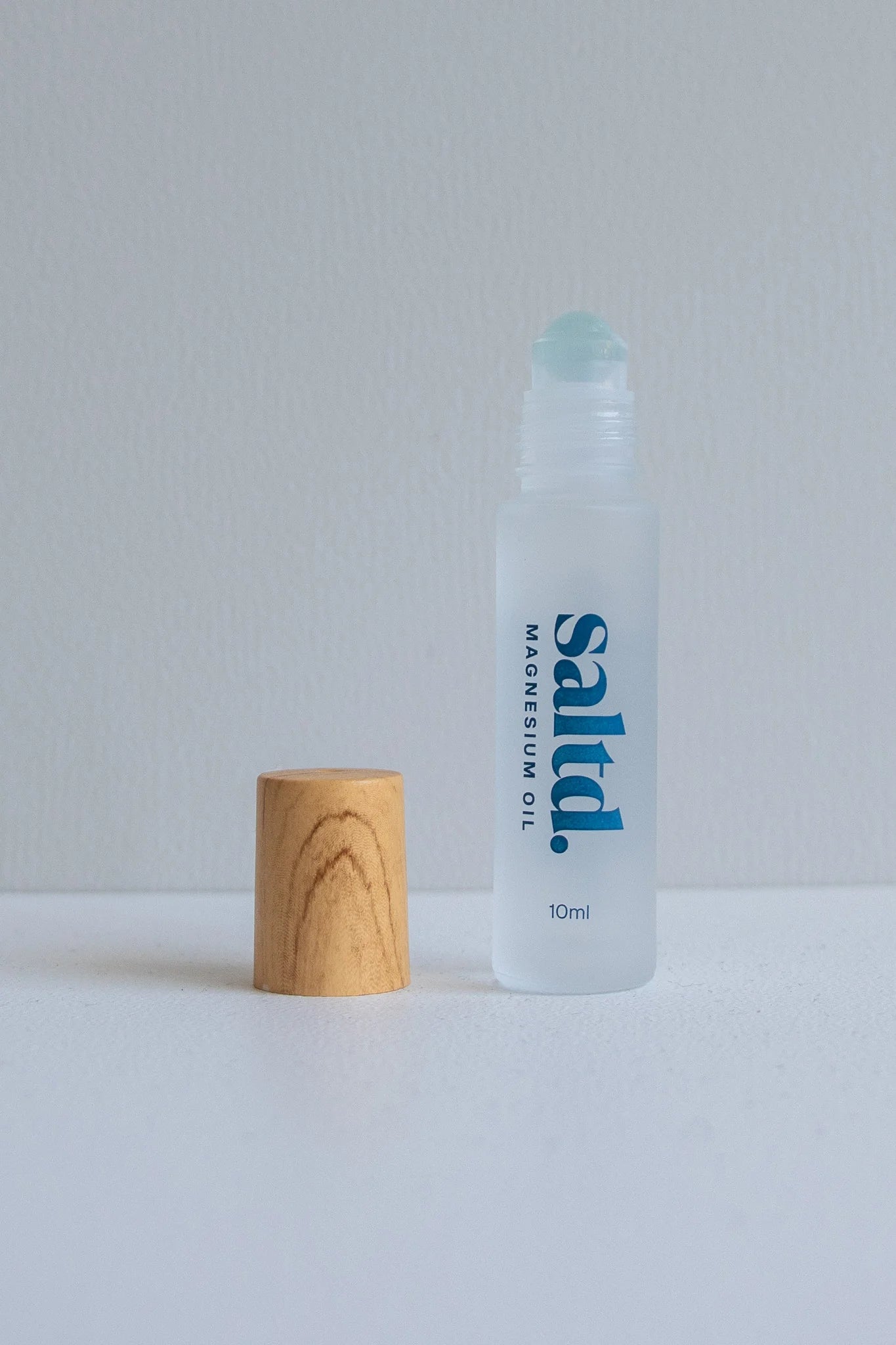 Clear bottle labeled 'saltd' with a wooden cap on a light gray background