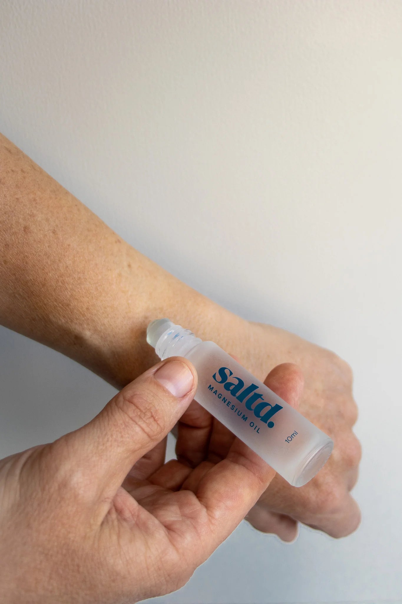 Person applying Saltd Magnesium Oil Roller to their wrist against a plain background