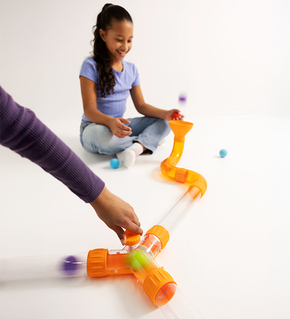 Child playing with Air Toobz Switch, a colourful toy tube set on a white surface